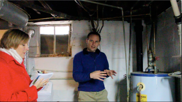 Dr. Whelton standing in a basement beside a hot water heater.